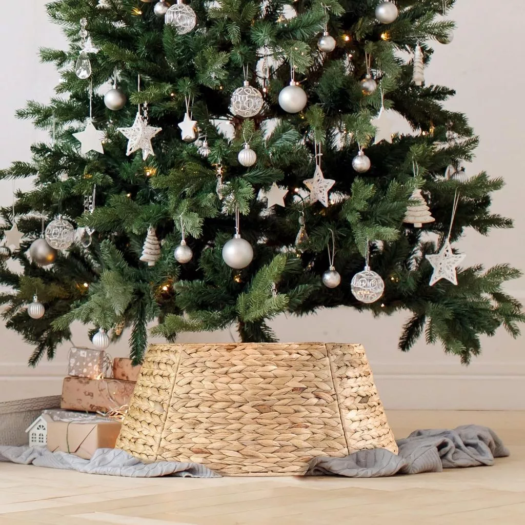  minimalist Christmas tree decorated with white ornaments, featuring a rustic, natural woven rattan tree skirt as a stylish base.